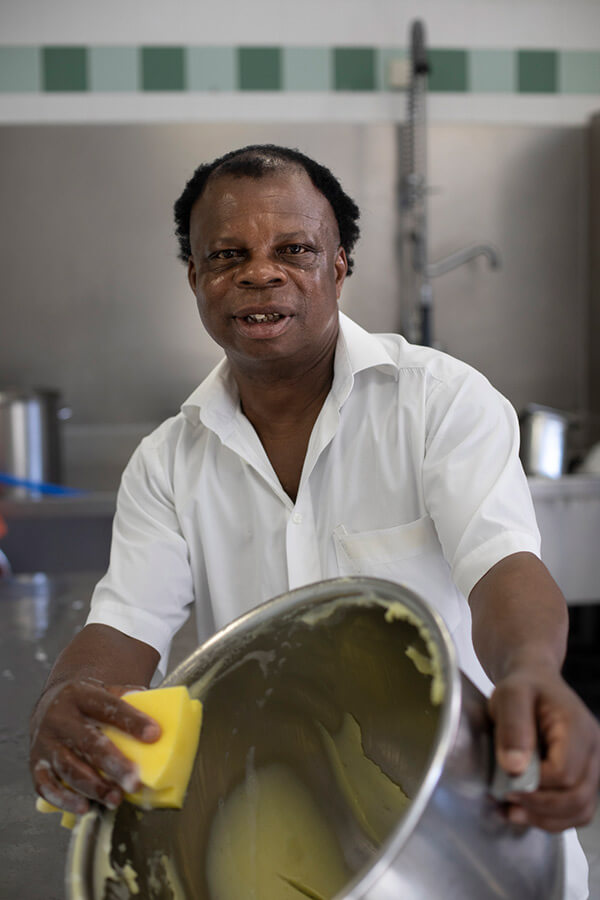 Chibuikem Omonata ist in der Küche und reinigt einen großen Topf.